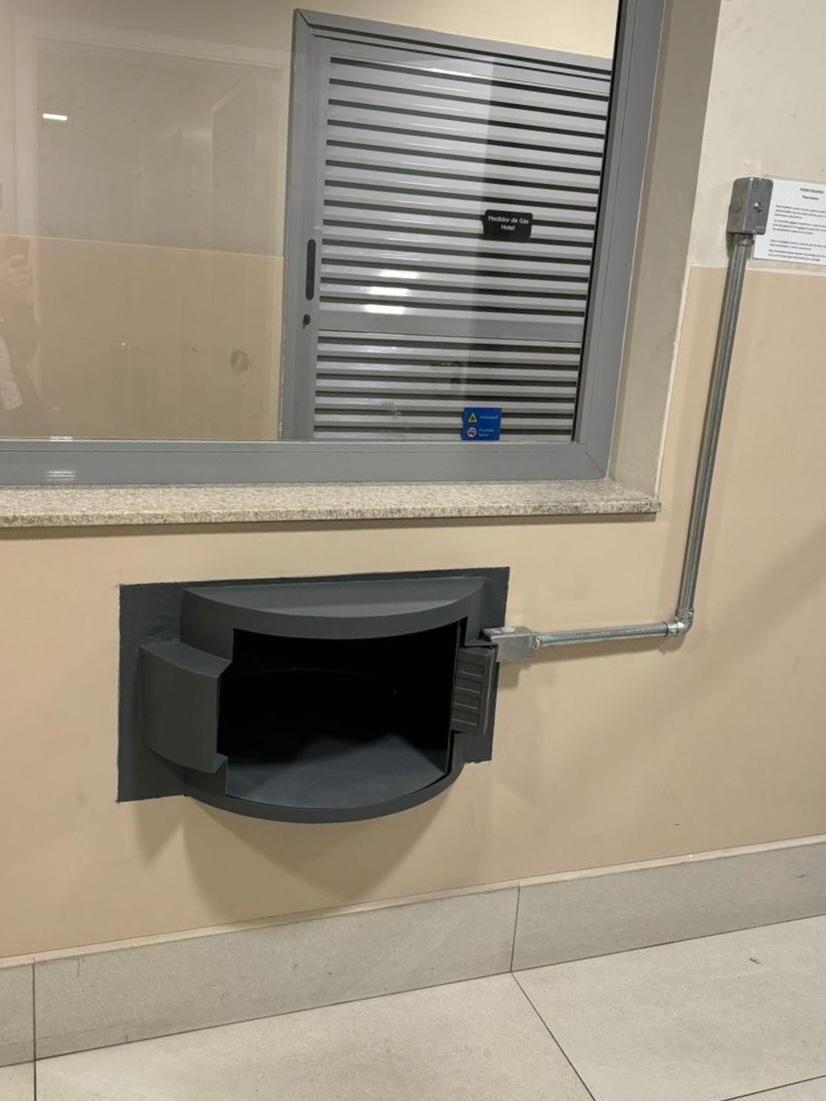 Passa-volume blindado giratório instalado em guardita, com acabamento aço e vidro fumê, integrado à parede